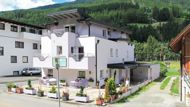 A modern building with a balcony, surrounded by potted plants and a car parked in front. - Amethyst by Interhome (Sölden)