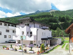 A modern building with a balcony, surrounded by potted plants and a car parked in front. - Amethyst by Interhome (Sölden)