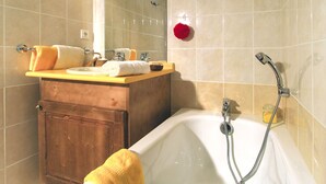 Une salle de bain avec une baignoire, un meuble en bois, un lavabo avec un miroir et un tapis de bain rouge.