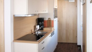 Una cocina compacta con gabinetes blancos, una cafetera negra y un microondas.
