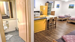 Kompakti oleskelutila, jossa on pieni keittiönurkkaus, ruokailualue ja pieni oleskelualue.