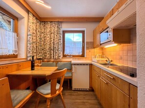 Kjøleskap, mikrobølgeovn, høy barnestol og kjøkkenutstyr