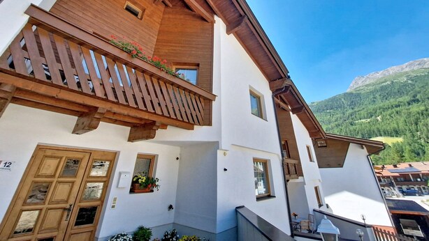 A two-story building with a wooden balcony, windows, and a mountain view. - Apartment Beate by Interhome (Sölden)