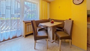 A dining area with a table and chairs, a clock on the wall, and a view through the window. - Apartment Beate by Interhome (Sölden)