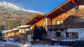 A chalet-style building with a sloped roof, wooden exterior, and a view of snow-covered mountains. - Apartment Beate by Interhome (Sölden)
