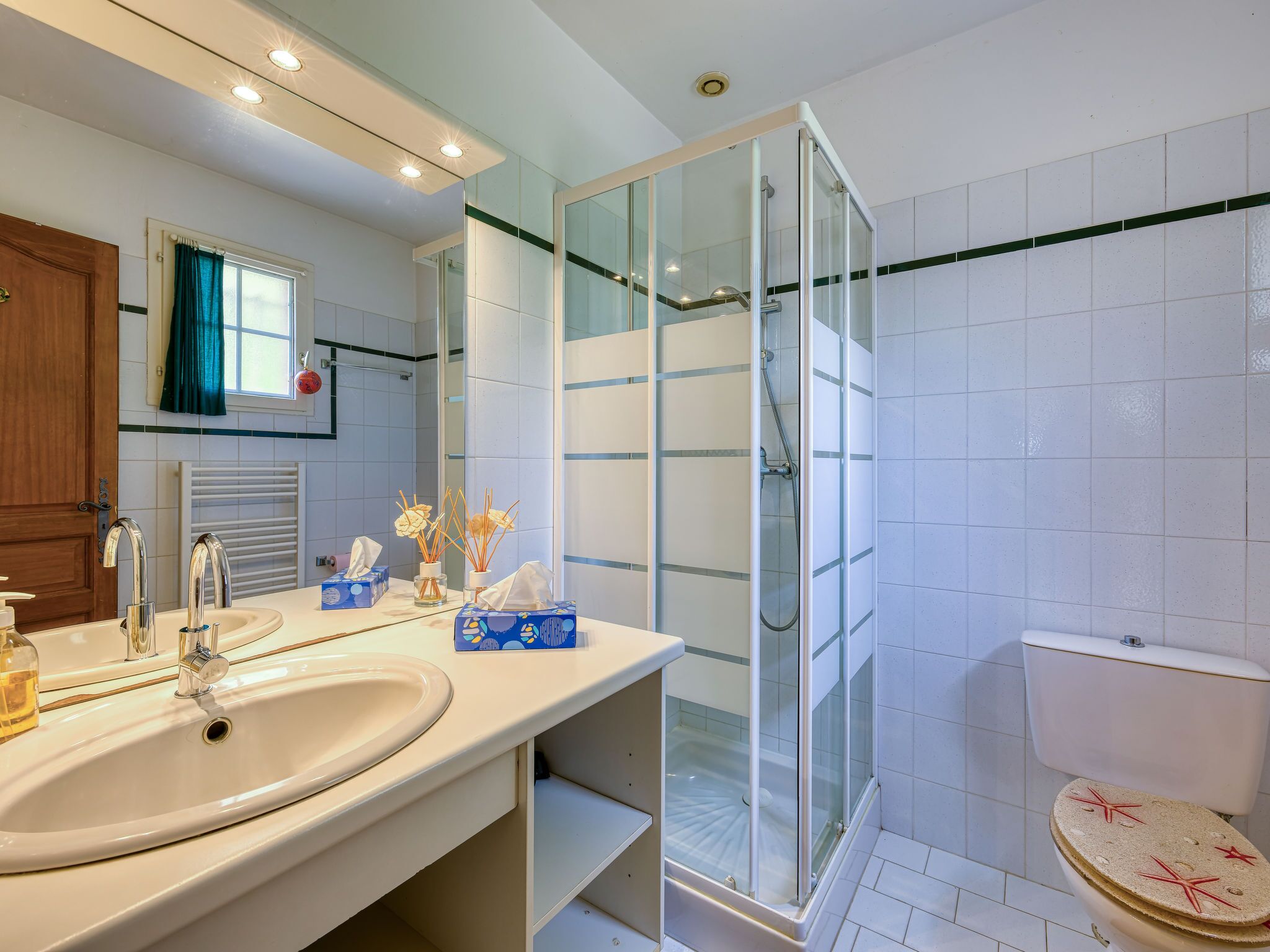 Ein Badezimmer mit Waschbecken, Duschkabine aus Glas und Toilette mit Sitzfläche mit Sternenmuster.