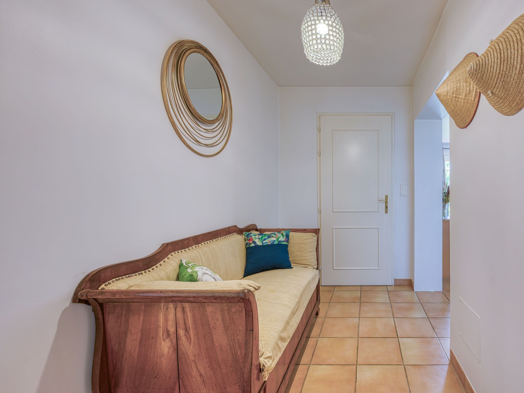 A hallway with a wooden bench, a white door, and a decorative mirror.