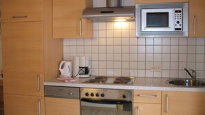 A kitchen with wooden cabinets, a microwave, a coffee maker, and a dishwasher. - Birkenheim by Interhome (Sölden)