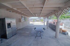 Enjoy al fresco dining on this outdoor patio with a table for four and a brick oven in the background.