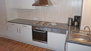 Une cuisine moderne avec des armoires blanches, une cuisinière en acier inoxydable, un four et un évier.