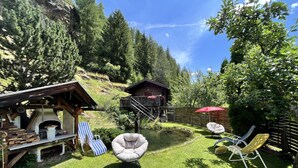 A rustic outdoor area with a wooden structure, a small pond, and lounge chairs.
