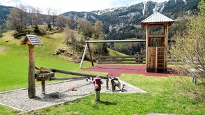 A playground with a swing set, a climbing structure, and a small wooden building.