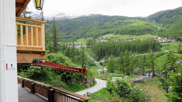 Une vue magnifique depuis un balcon donnant sur une vallée, avec un pont en bois, un mur de pierre et un escalier en pierre.