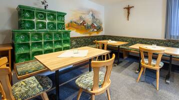 Ein Restaurant mit Holztischen und -stühlen, einer grünen Wand aus Mosaiksteinen und einem Wandgemälde eines Pferdes und Berges.