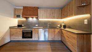 Une cuisine moderne avec des meubles en bois, un four encastré, un lave-vaisselle et un four à micro-ondes.