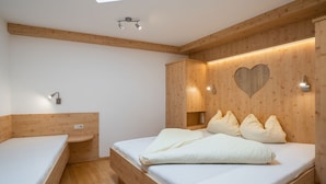 Un dormitorio con tragaluz, paredes de madera, una cama con almohadas y una mesita de noche.