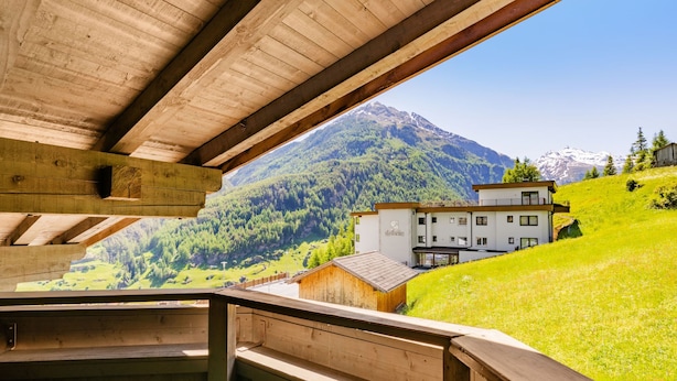 Una cabaña de madera con balcón que da a un paisaje montañoso.