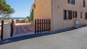 A building with a beige exterior, a wooden gate, and a view of the sea.