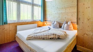 A wooden room with a bed, a window with curtains, and a wooden wardrobe. - Apartment Nadine by Interhome (Sölden)