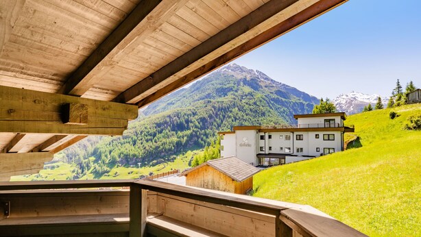 Una cabaña de madera con balcón que da a un paisaje montañoso.