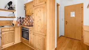 Una cocina compacta con armarios de madera, horno integrado y un lavamanos.
