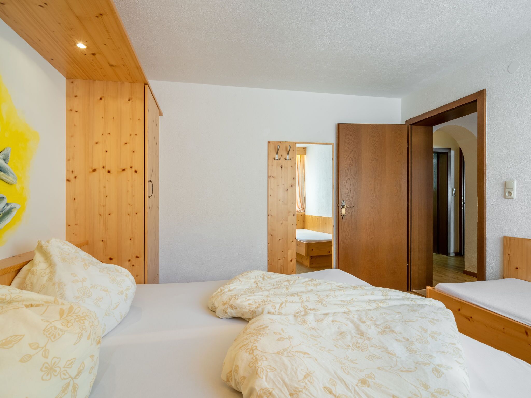Un dormitorio con paredes de madera, una cama con ropa de cama floral y un armario de madera.