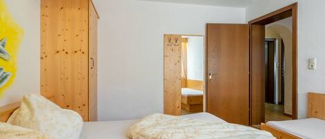 Un dormitorio con paredes de madera, una cama con ropa de cama floral y un armario de madera.