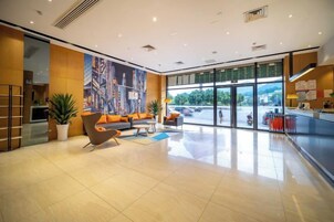 Un vestíbulo de hotel con una zona de estar, una recepción y ventanas amplias.