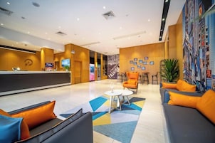 Un vestíbulo de hotel con mostrador de recepción, zona de estar y una pared decorada con cuadros.