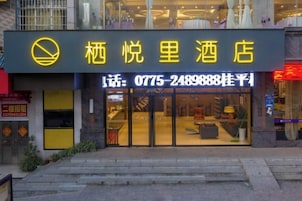 Un hotel con un letrero amarillo llamativo, un número de teléfono visible y una entrada de vidrio.