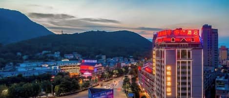A hotel with multiple floors, a prominent entrance, and a view of surrounding buildings and hills.