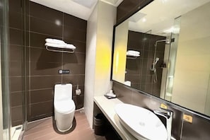 A modern bathroom with a toilet, sink, and a large mirror.