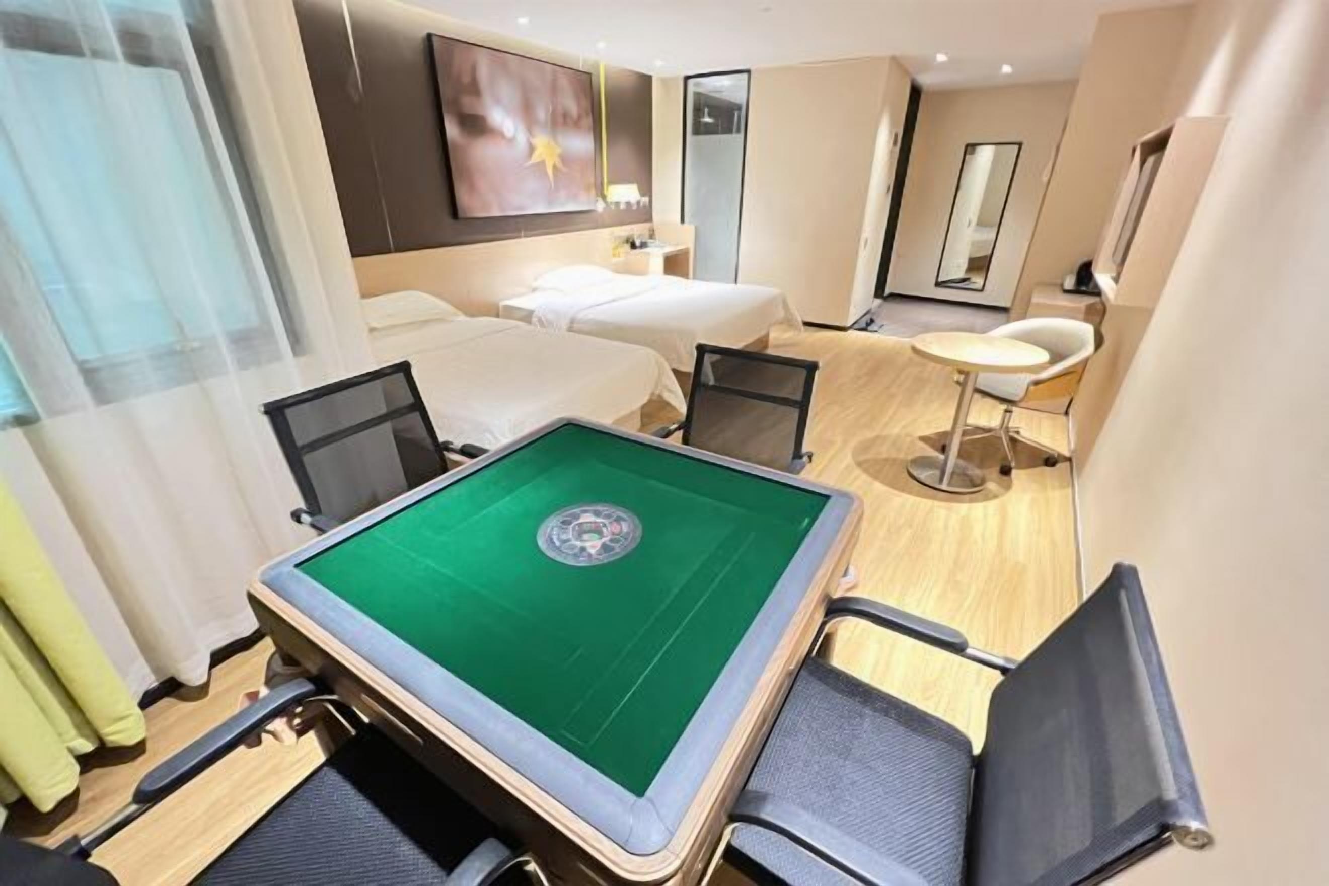 Habitación de hotel con mesa de billar, dos camas, una zona de estar con una silla y un espejo.