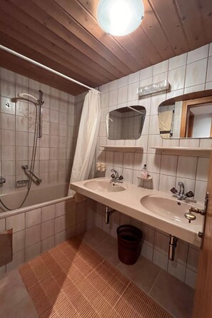 A bathroom with two sinks, a shower, and a mirror.