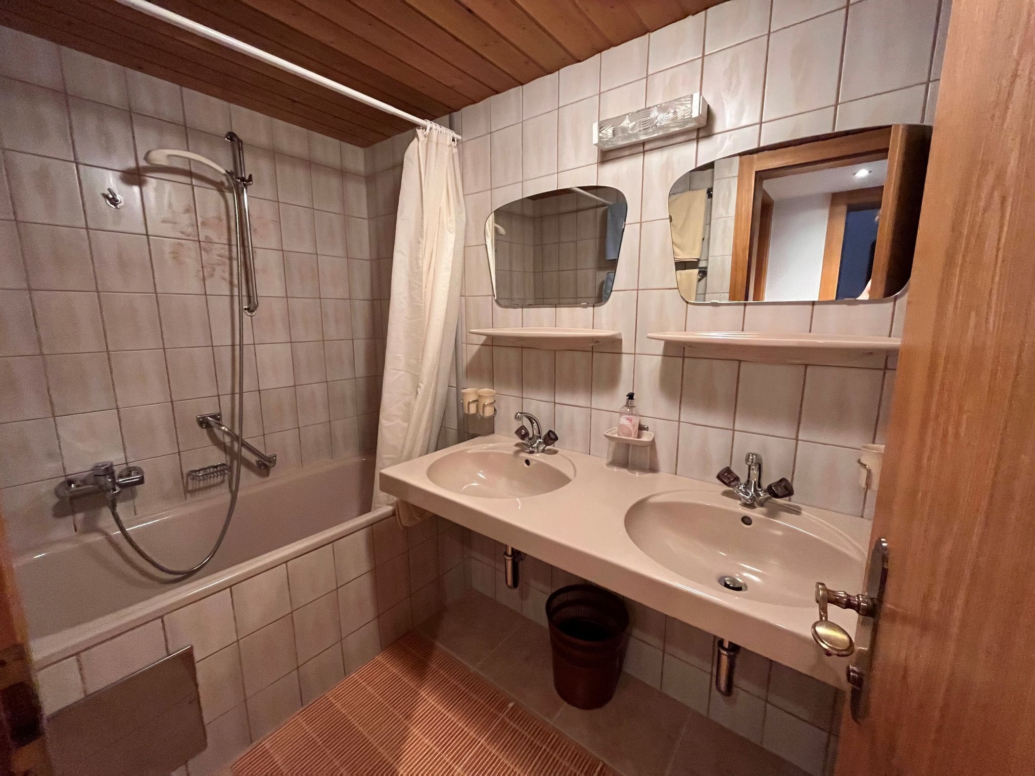 A bathroom with two sinks, a shower, and a mirror.