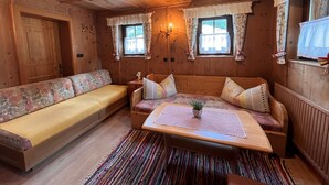 A cozy cabin interior with a sofa, a small table with a plant, and two windows with curtains. - Hannelore by Interhome (Sölden)