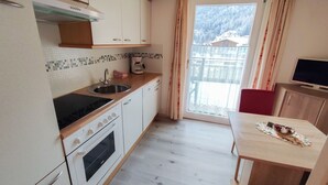 Uma cozinha compacta com fogão, forno, pia e um espaço de refeições com mesa e cadeiras.