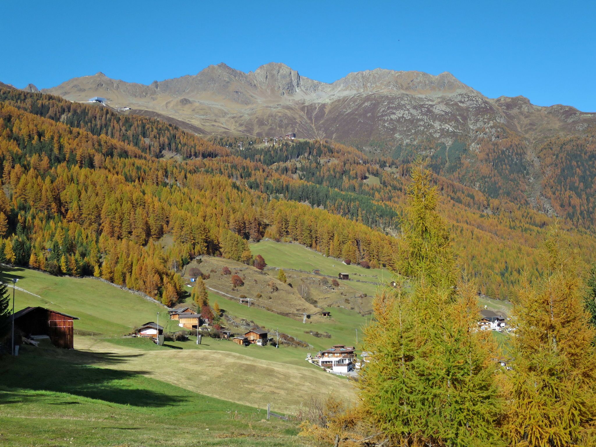 A mountainous landscape with a small village, houses, and a clear sky.