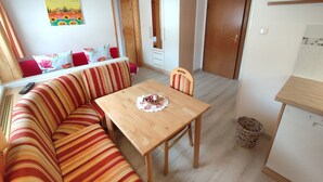 Un espacio de sala acogedor con un sofá a rayas, una mesa de comedor de madera y un cuadro colorido en la pared.