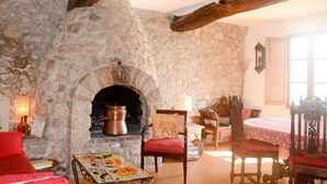 Una habitación rústica con chimenea de piedra, muebles de madera y un ventanal grande.