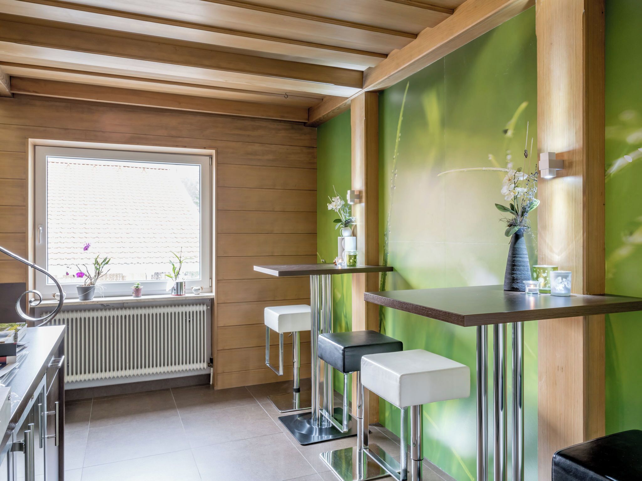 Eine moderne Küche mit Holzvertäfelung, einem großen Fenster und Barhocker.
