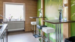 Een moderne keuken met houten lambrisering, een groot raam en barstoelen.