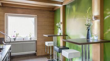 Eine moderne Küche mit Holzvertäfelung, einem großen Fenster und Barhocker.