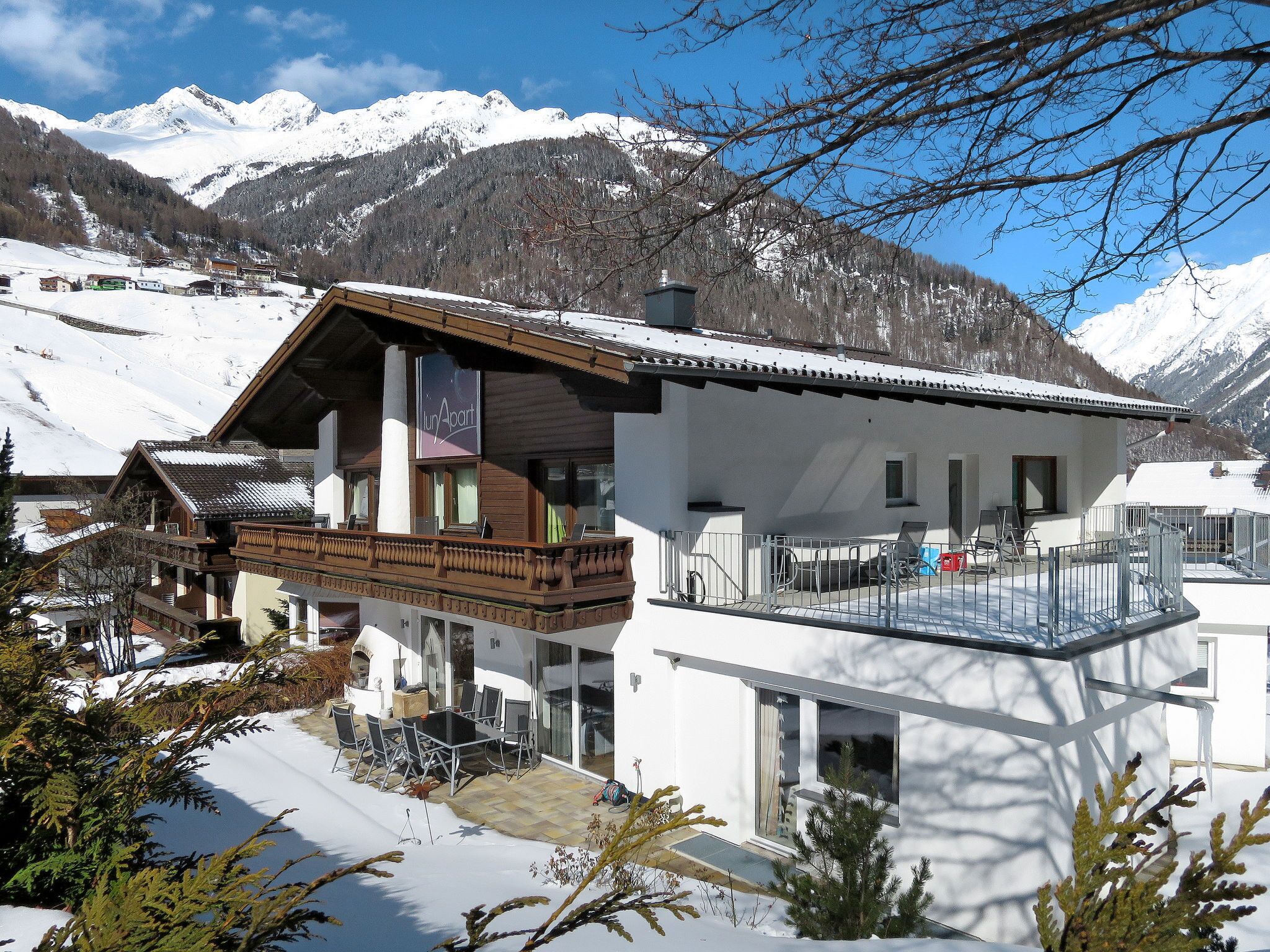 Ein modernes Chalet mit Balkon, Essbereich und Blick auf schneebedeckte Berge.