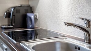 Een keuken met een roestvrijstalen spoelbak, een koffiezetapparaat en een broodrooster.