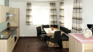 Une cuisine de taille réduite avec un coin repas, comprenant une table avec des chaises et un banc.