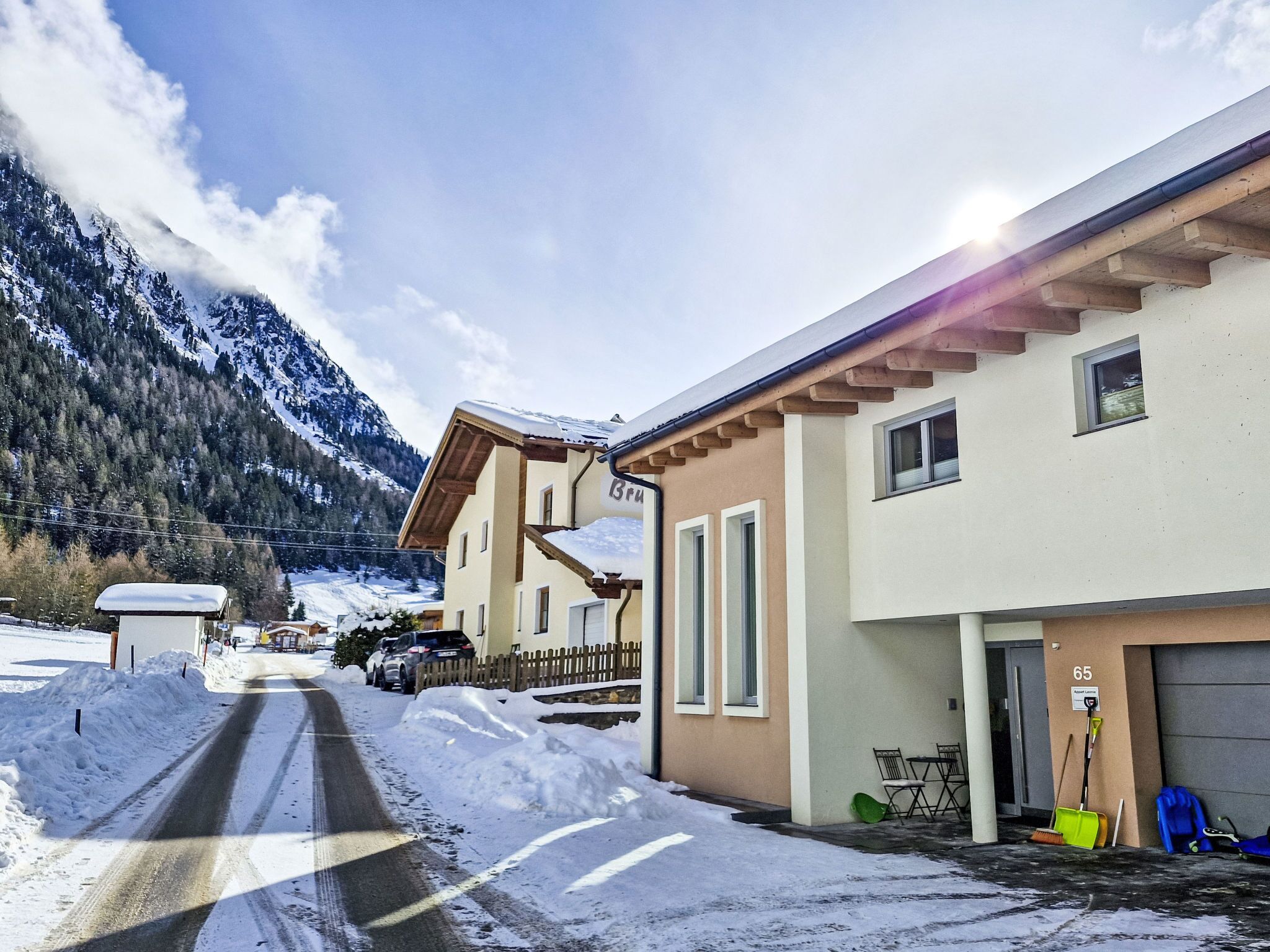 A snow-covered street with buildings, a road, and mountains in the background.