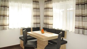 Un coin repas avec une table en bois, des chaises noires et des rideaux à rayures.