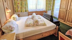 A cozy room with a wooden bed, floral curtains, and a small table with a lamp. - Wiesenhof by Interhome (Längenfeld)