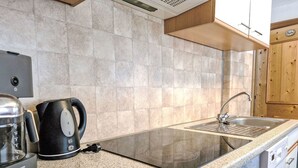 A kitchen with a granite countertop, a stainless steel sink, a coffee maker, and a kettle. - Wiesenhof by Interhome (Längenfeld)